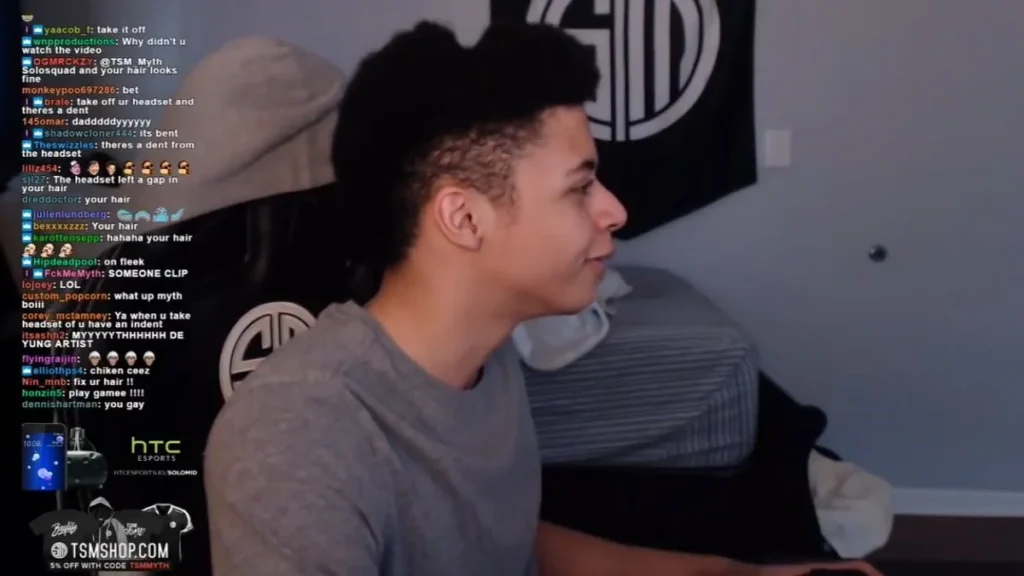 Gamer with headphone hair indentation, sitting at a desk, with a TSM banner and chat messages in the background.